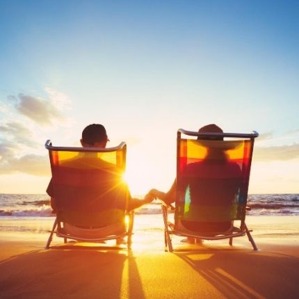 photo of a couple in lounge chairs watching the sunset at the ocean