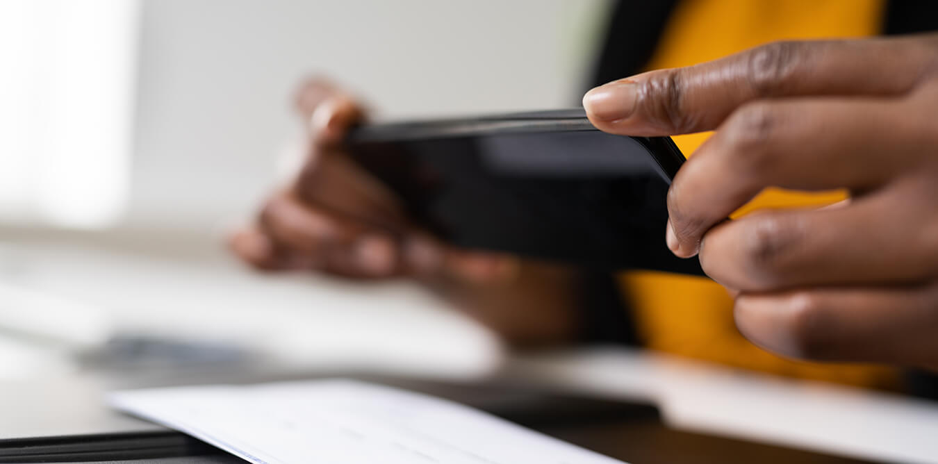 photo of two hands with a mobile phone taking a photo of a check for mobile deposit