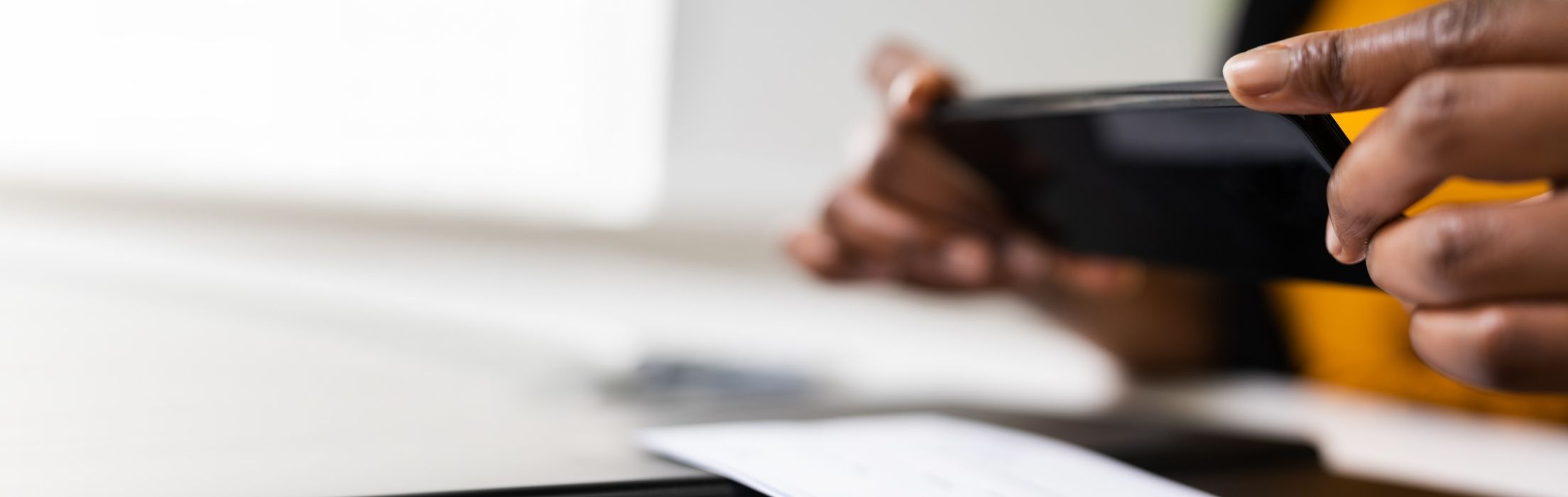 Mobile Deposit for Business. Photo of hands holding an phone and making a mobile check deposit.